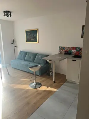 a living room with a blue couch and a table at Ruczaj Cozy Room in Kraków