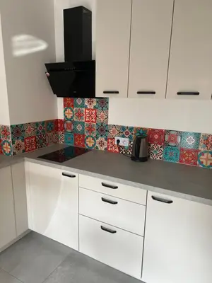 a kitchen with white cabinets and tiles on the wall at Ruczaj Cozy Room in Kraków