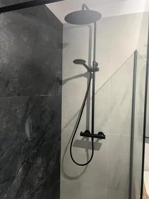 a shower with a light on the wall in a bathroom at Ruczaj Cozy Room in Kraków