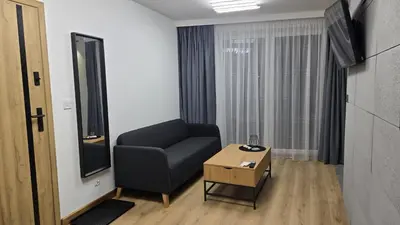 a living room with a black chair and a table at Apartamenty Żurawia 1- Piętro 2 in Kraków