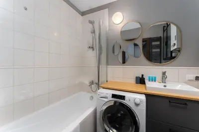 a bathroom with a washing machine and a sink at Bocheńska Modern Apartment by BookingHost in Kraków
