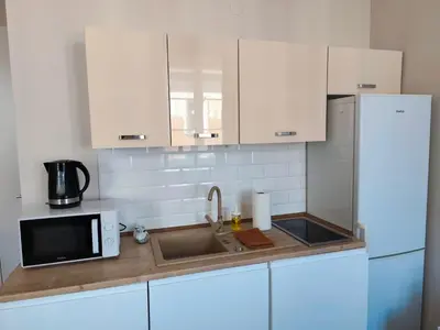 a kitchen with white cabinets and a sink and a microwave at Krakow City Stay - City Vibes, Historic Charm in Kraków