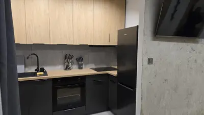 a kitchen with black appliances and wooden cabinets at Apartamenty Żurawia 1 - Piętro 1 in Kraków