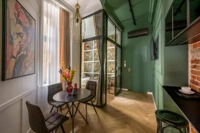 a room with green walls and a table and chairs at Colora Apartments by MB Apartments in Kraków