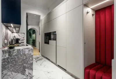 a kitchen with white cabinets and a red bench at Colora Apartments by MB Apartments in Kraków