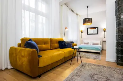 a living room with a yellow couch and a bed at Apartament Tenczyńska in Kraków