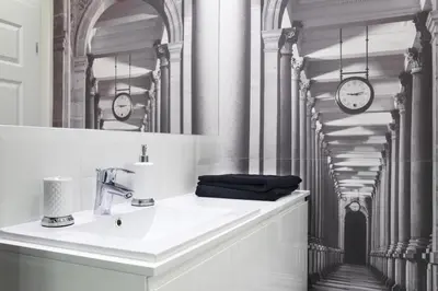 a bathroom with a sink and a mirror and clocks at Apartament Tenczyńska in Kraków