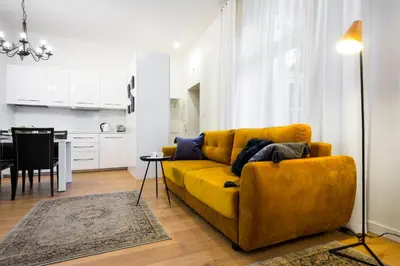 a living room with a yellow couch and a kitchen at Apartament Tenczyńska in Kraków