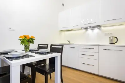 a kitchen with white cabinets and a table with chairs at Apartament Tenczyńska in Kraków