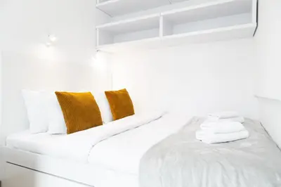 a white room with a bed with towels on it at Househost Apartment Plac Na Groblach 5 in Kraków