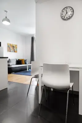 a living room with a table and two white chairs at Househost Apartment Plac Na Groblach 5 in Kraków