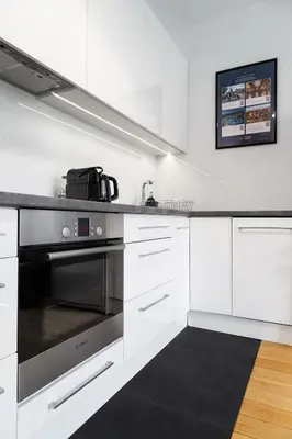 a kitchen with white cabinets and a stainless steel oven at Househost Apartment Plac Na Groblach 5 in Kraków