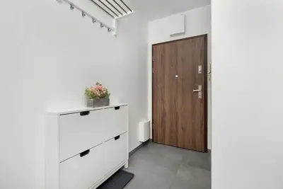 a room with a white dresser and a wooden door at Aleja Kijowska Kraków Modern Apartment with Balcony and Parking by Noclegi Renters in Kraków