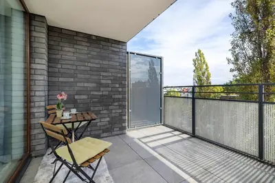 a patio with a table and chairs on a balcony at Aleja Kijowska Kraków Modern Apartment with Balcony and Parking by Noclegi Renters in Kraków