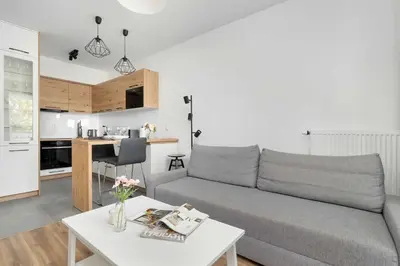 a living room and kitchen with a couch and a table at Aleja Kijowska Kraków Modern Apartment with Balcony and Parking by Noclegi Renters in Kraków