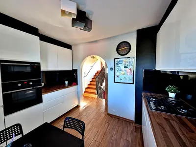 a kitchen with white cabinets and a hallway with a staircase at Dom w Kryspinowie in Kryspinów