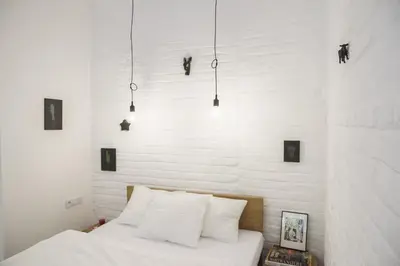 a bedroom with white walls and a bed with white pillows at Garden Studio in Kraków