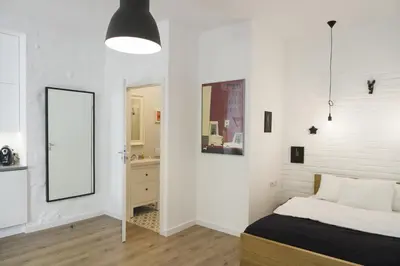 a white bedroom with a bed and a mirror at Garden Studio in Kraków