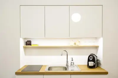 a kitchen with white cabinets and a sink at Garden Studio in Kraków