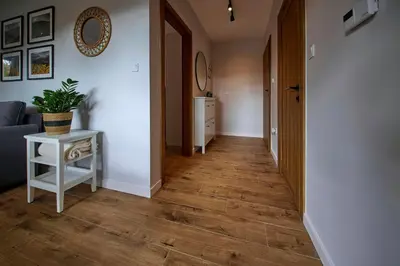 a hallway with a table and a couch and wooden floors at Przytulne M w Pcimiu in Pcim