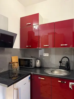 a kitchen with red cabinets and a sink at Cozy Central Kraków Studio - Walk to Wawel - Fast Wi-Fi & Smart TV in Kraków