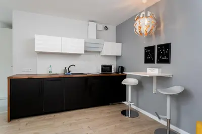 a kitchen with black and white cabinets and a table at Kraków Grzegórzki Deluxe Studio by BookingHost in Kraków