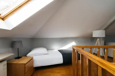 a bedroom with a white bed and a staircase at Native Apartments Warszauera 3 in Kraków