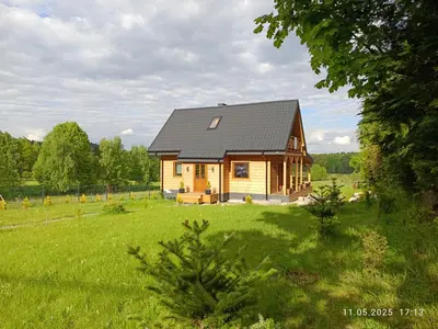a small wooden house in a field of green grass at Jura - Chata pod Grodziskiem Pańskim in Domaniewice
