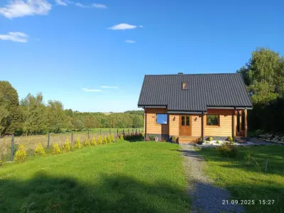 a wooden cabin in a field with a grass yard at Jura - Chata pod Grodziskiem Pańskim in Domaniewice