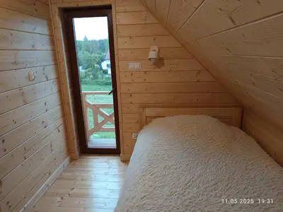 a bed in a wooden room with a window at Jura - Chata pod Grodziskiem Pańskim in Domaniewice