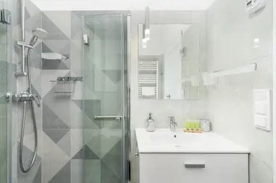 a white bathroom with a shower and a sink at Househost Apartment Krowoderska 64 in Kraków