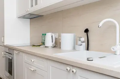 a white kitchen with a sink and a counter top at Househost Apartment Krowoderska 64 in Kraków