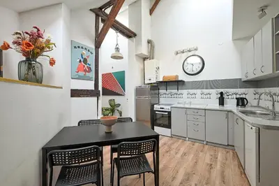 a kitchen with a table and chairs and a clock at Urbannest-Augustiańska 4 in Kraków