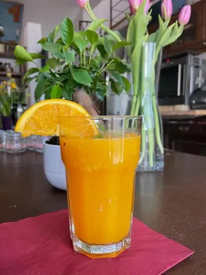 a glass of orange juice sitting on a table at Villatopol Art Hostel in Rząska