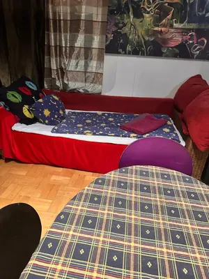 a bed sitting in a room with a red couch at Villatopol Art Hostel in Rząska