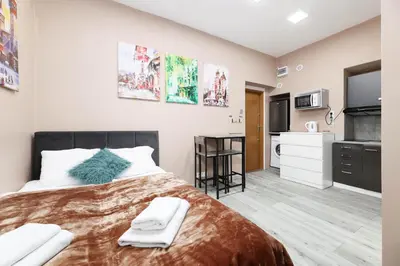 a bedroom with a large bed and a kitchen at Zyblikiewicza 11 by Homeprime in Kraków