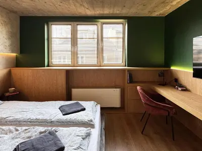 a room with two beds and a desk and window at Green Point - Design Apartaments in Kraków