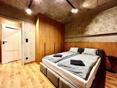 a bedroom with a large bed with wooden walls at Green Point - Design Apartaments in Kraków