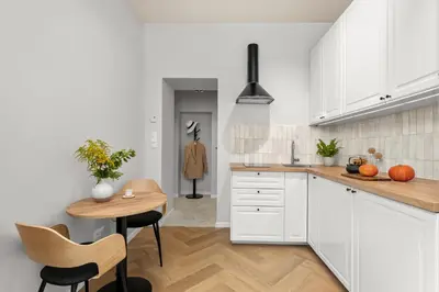 a kitchen with white cabinets and a wooden table at Apartament Lea Garden in Kraków