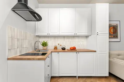 a kitchen with white cabinets and a sink at Apartament Lea Garden in Kraków