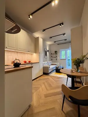 a kitchen and a living room with a table at Apartament Lea Garden in Kraków