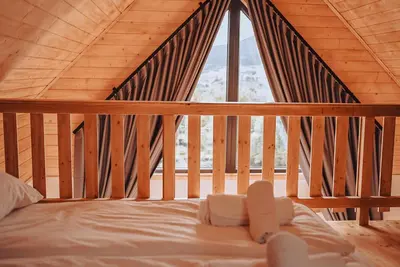 a bed in a wooden room with a window at Zachód Beskidu domek z Jacuzzi na wyłączność in Nowe Rybie