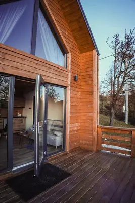 an exterior view of a wooden house with sliding glass doors at Zachód Beskidu domek z Jacuzzi na wyłączność in Nowe Rybie