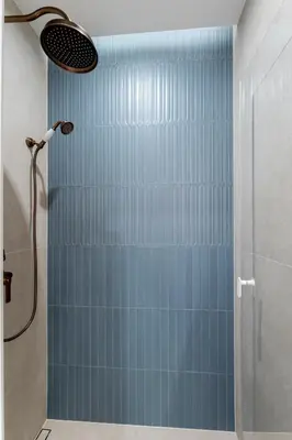a bathroom with a shower with blue tiles at San Benedetto Stylish Apartments in Kraków