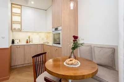 a kitchen with a wooden table with a vase of flowers at San Benedetto Stylish Apartments in Kraków
