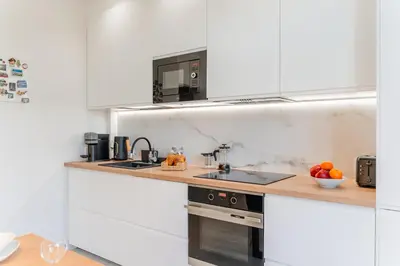 a white kitchen with a sink and a stove at Kraków Suite - Balcony, Workspace - by Rentujemy in Kraków