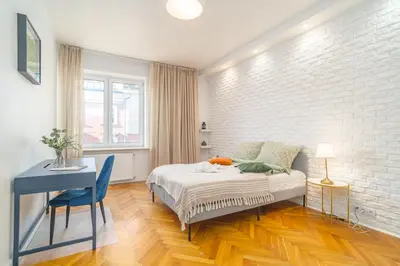 a bedroom with a bed and a desk and a white brick wall at Kraków Suite - Balcony, Workspace - by Rentujemy in Kraków