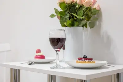 a table with a glass of wine and a piece of cake at CracWoW S31 Apartment in Kraków