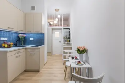 a kitchen with white cabinets and a table and chairs at CracWoW S31 Apartment in Kraków