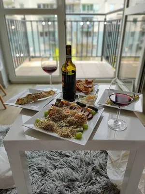 a table with plates of food and a bottle of wine at Cozy Studio for a Couple - 10 min from the airport in Kraków